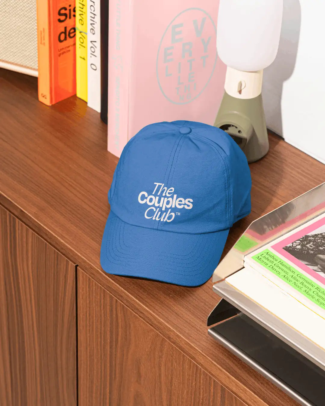 The Couples Club merch design: blue cap with stacked white wordmark logo