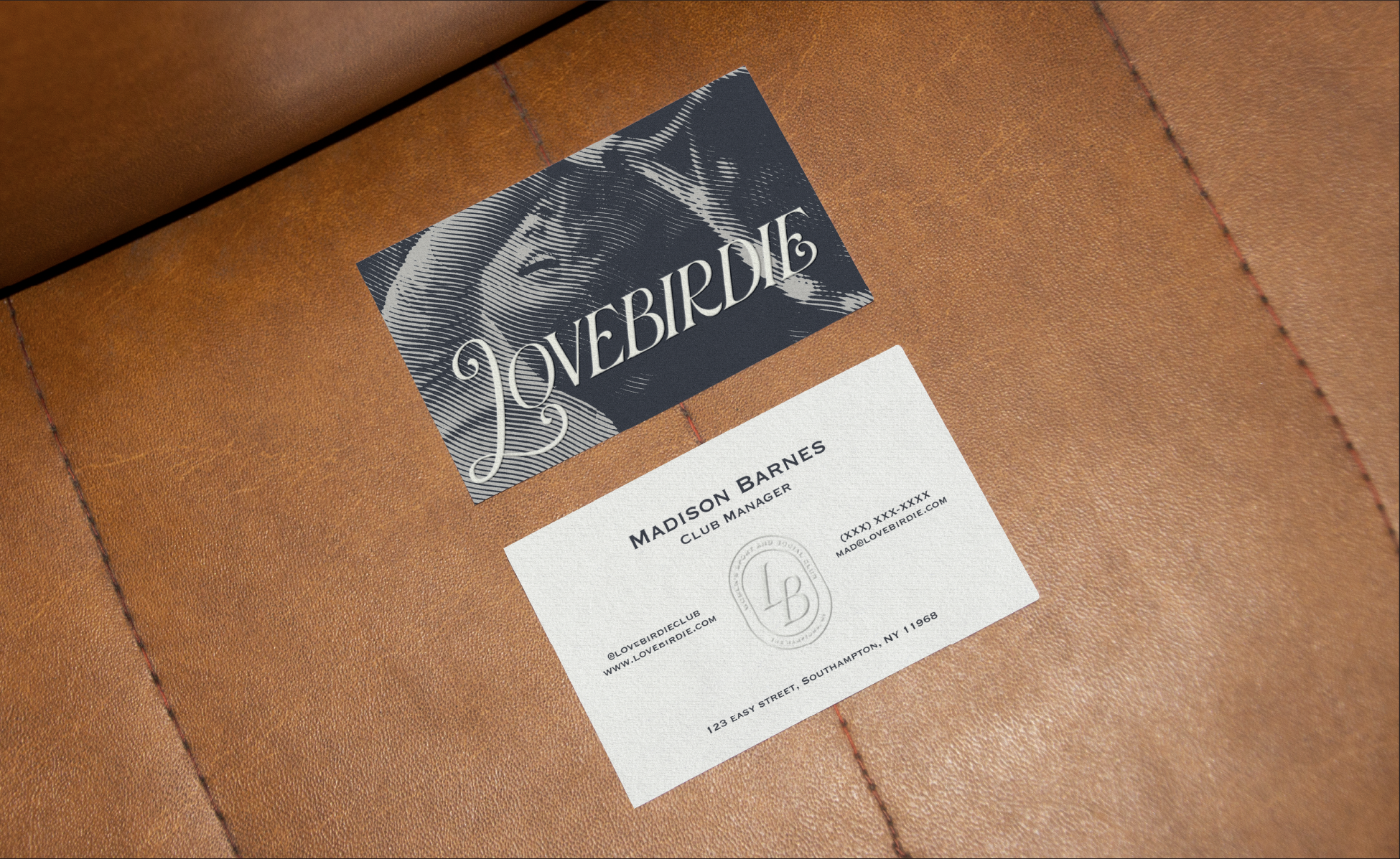 Front and back of business cards on a brown leather surface, one titled 'LOVEBIRDIE' and the other with embossed submark logo and contact information
