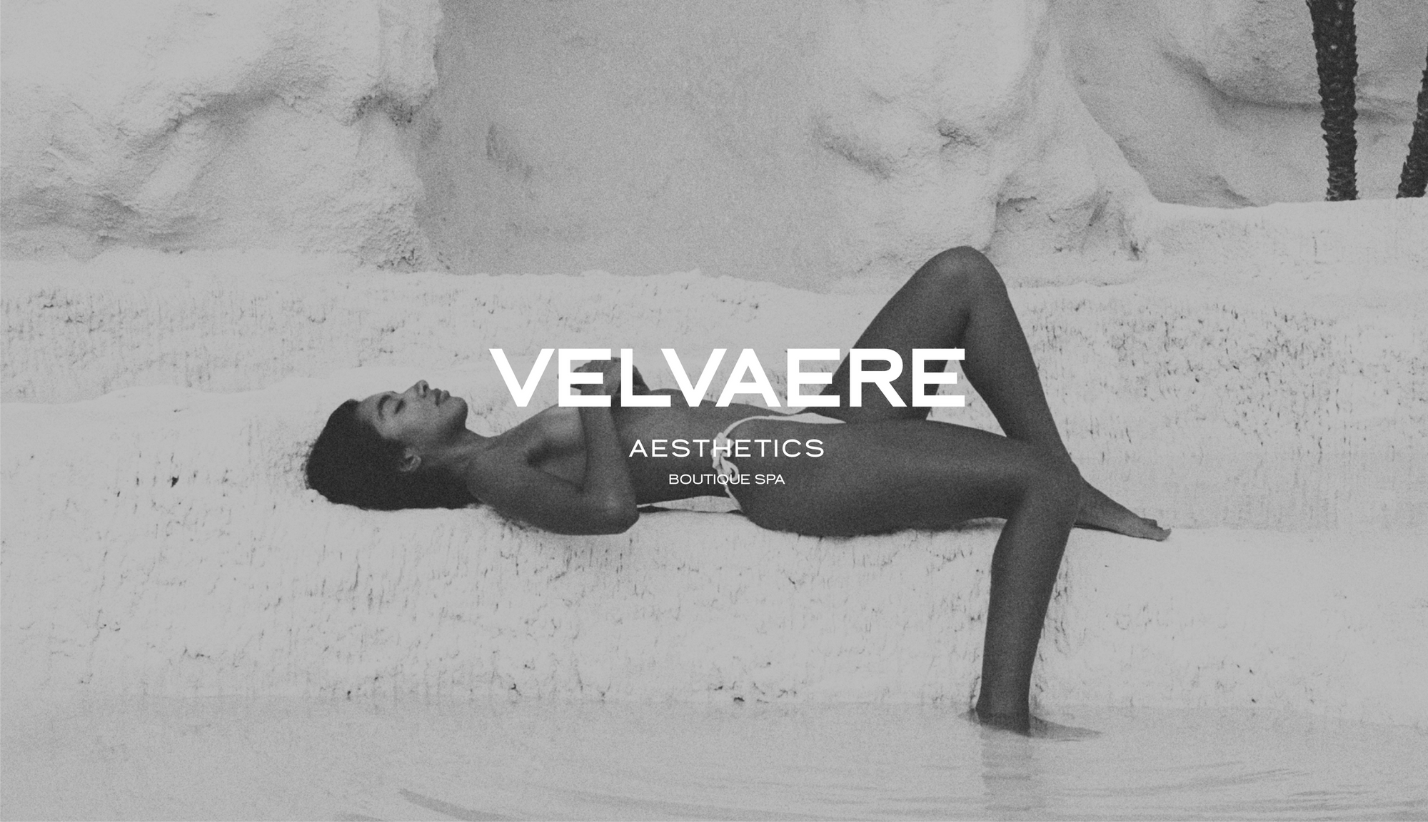 Person lying on a rocky surface with 'Velvaere Aesthetics' branding.