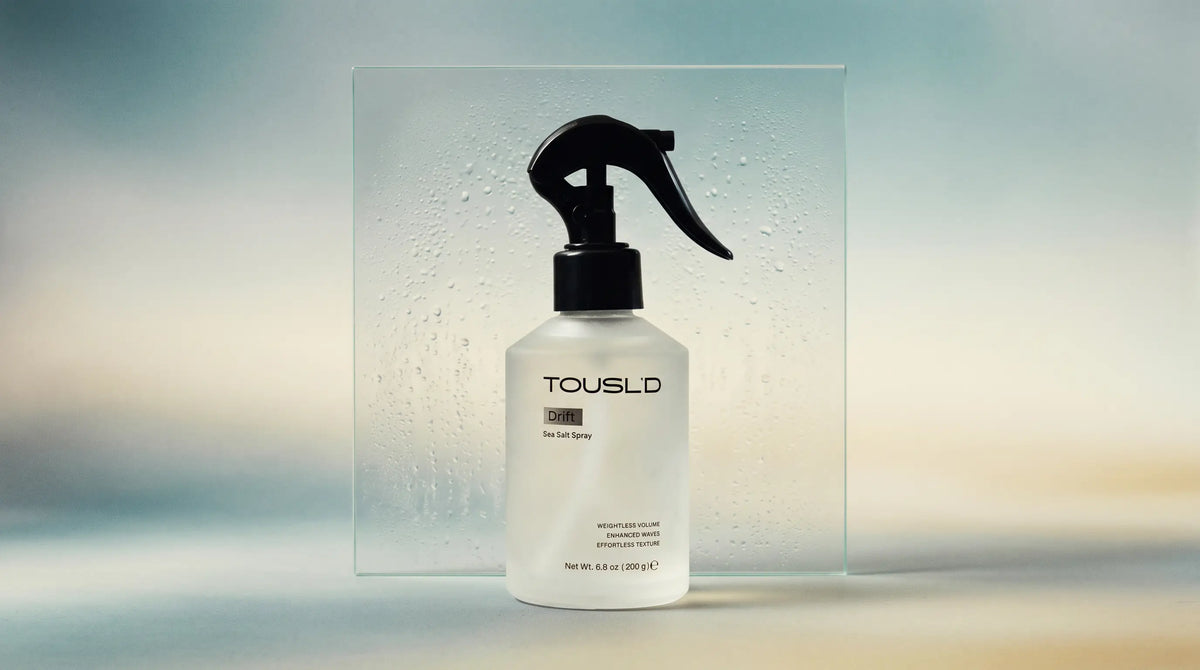 Tousl’d salt spray glass bottle in a minimal studio setting